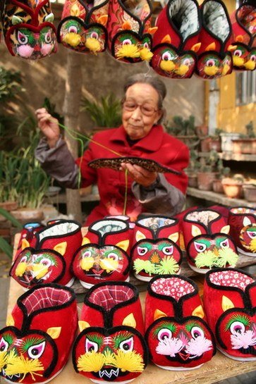 An elderly shows displays tiger-like shoes made by hand in time for winter in Tancheng town, Linyi city of China&apos;s east Shandong province on Nov 7, 2010. [Xinhua]