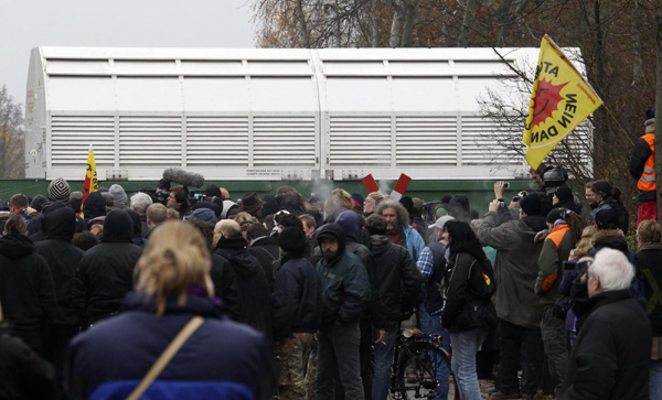 Anti-nuclear protestors watch as a Castor nuclear waste container arrives by train at Dannenberg Nov 8, 2010. [China Daily/Agencies]