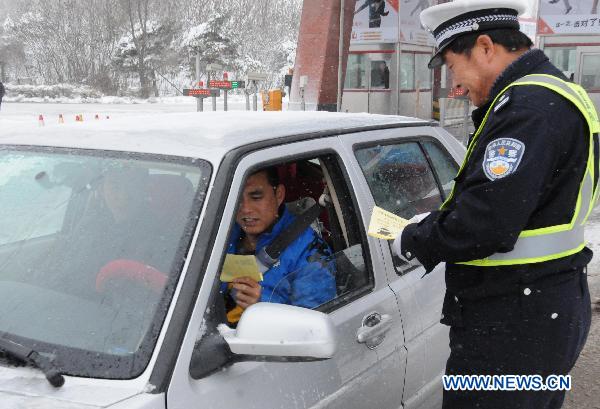 A traffic policeman (R) works at the Yingchengzi toll station on the Changchun-Liaoyuan Highway in northeast China's Jilin Province. Traffic control measures have been taken in parts of Jilin's provincial highway system after heavy snowfall hit most parts of Jilin since Sunday evening. 