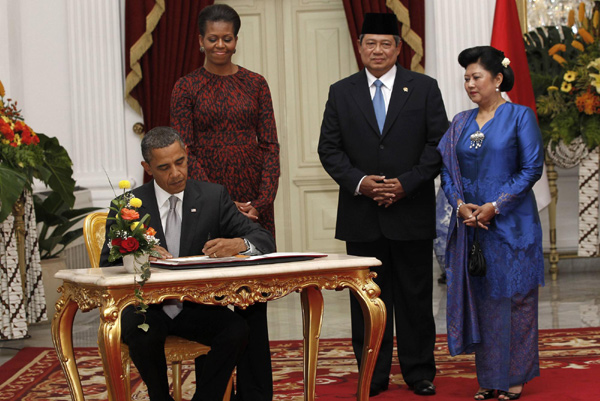 US President Barack Obama, accompanied by first lady Michelle Obama, signs a book while Indonesian president Susilo Bambang Yudhoyono and Kristiani Herawati look on at Merdeka Palace in Jakarta Nov 9, 2010. [China Daily/Agencies]