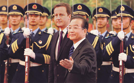 Premier Wen Jiabao accompanies British Prime Minister David Cameron as they review a guard of honor at a welcome ceremony in the Great Hall of the People in Beijing on Tuesday. [Wu Zhiyi/China Daily]　