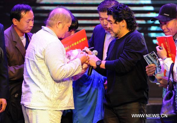 Argentine soccer legend Diego Maradona (L) signs for the anchorman at a charity activity in Hefei, capital of east China's Anhui Province, on Nov. 9, 2010. Maradona arrived Hefei Tuesday on his charity tour to raise money for a project of the Chinese Red Cross Foundation, aimed at helping poor people who suffer from cancer. (Xinhua/Guo Chen) 