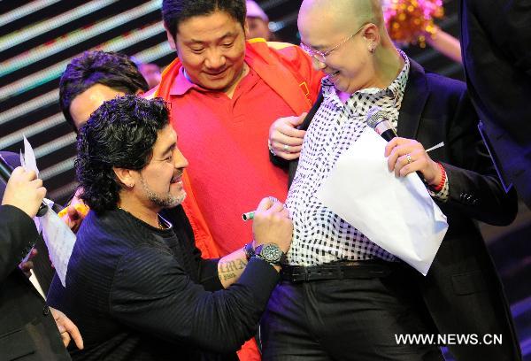 Argentine soccer legend Diego Maradona (L) signs for the anchorman at a charity activity in Hefei, capital of east China's Anhui Province, on Nov. 9, 2010. Maradona arrived Hefei Tuesday on his charity tour to raise money for a project of the Chinese Red Cross Foundation, aimed at helping poor people who suffer from cancer. (Xinhua/Guo Chen)