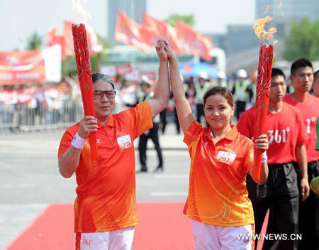 Torchbearer Fok Tsun Ting (L) and Dawa Yangzom pose with the torches during the Torch Relay for the 16th Asian Games in Guangzhou, South China's Guangdong Province, Nov. 9, 2010. Dawa Yangzom lit a flame at the foot of Mount Tangula to start the Torch Relay for the Beijing Asian Games in 1990 at the age of 14. (Xinhua/Liu Dawei)