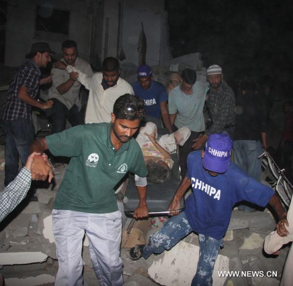 People transfer an injured woman from the blast site in southern Pakistan's Karachi on Nov. 11, 2010. At least 30 people including 12 policemen were killed and 150 others injured in a powerful blast that went off Thursday night in the downtown area of Karachi, the largest industrial city in southern Pakistan. [Arshad/Xinhua]