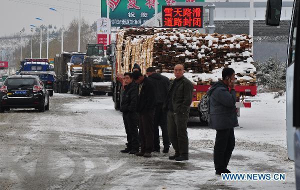 People and vehicles are stranded at the entrance of the Harbin-Mudanjiang highway in northeast China's Heilongjiang Province, Nov. 12, 2010. The highway, shut down due to the heavy snow from late Thursday, was reopened to small vehicles at the noon of Friday. The provincial meteorologicial department issued a blue warning signal of snow on late Thursday. 