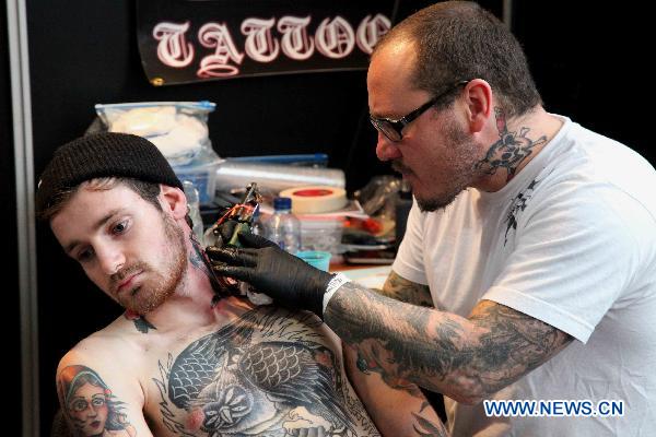 A tattoo artist tattoos for a guest during the first Brussels international tattoo expo in Brussels, Nov. 13, 2010. [Xinhua] 