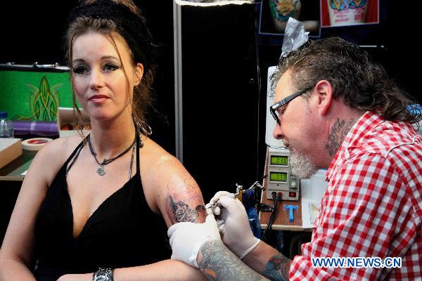 A tattoo artist tattoos for a guest during the first Brussels international tattoo expo in Brussels, Nov. 13, 2010. [Xinhua] 