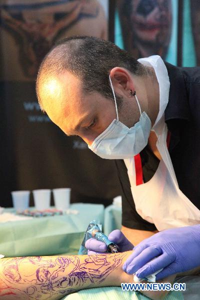 A tattoo artist tattoos for a guest during the first Brussels international tattoo expo in Brussels, Nov. 13, 2010. [Xinhua] 