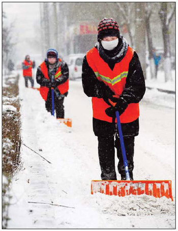 Sanitation workers shovel snow on Saturday from the streets of Harbin, capital of Heilongjiang province. To cope with the heavy snow that fell since Thursday, the city mobilized 23,000 workers and 500 vehicles to clear the streets. [Xinhua] 
