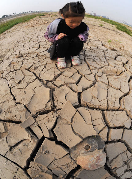 A girl looks at the dried river bed of Dongting Lake in Yueyang in Hunan Province yesterday. The Boyang lake's water level is the lowest in recent years at 21.77 meters due to lack of water at the upper stream of the Yangtze River and little rainfall in the province. [Shanghai Daily] 