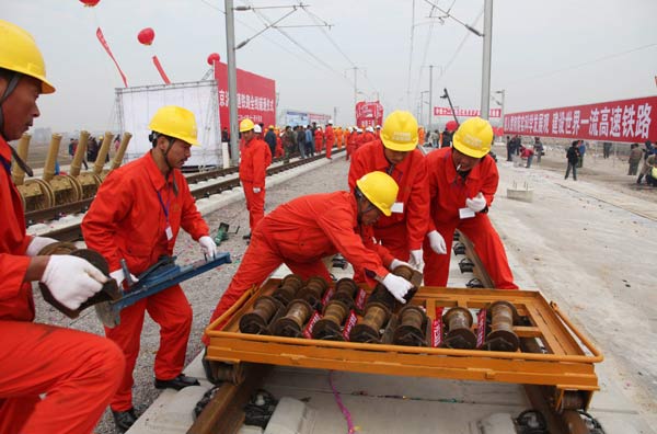 Workers lay the last track for the Beijing-Shanghai high-speed railway in Bengbu, Anhui province, on Monday. Track-laying work for the long-anticipated Beijing-Shanghai high-speed railway stood complete when Railways Minister Liu Zhijun tightened the line&apos;s last bolt on a windy Monday morning. [China Daily] 