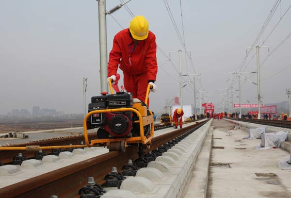 Workers lay the last track for the Beijing-Shanghai high-speed railway in Bengbu, Anhui province, on Monday. Track-laying work for the long-anticipated Beijing-Shanghai high-speed railway stood complete when Railways Minister Liu Zhijun tightened the line&apos;s last bolt on a windy Monday morning. [China Daily] 