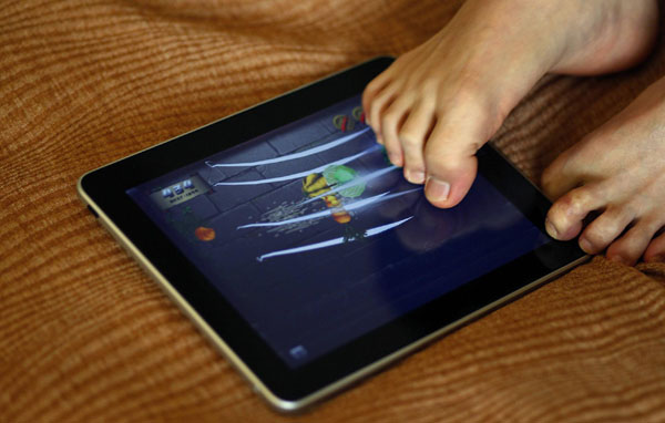 Pianist Liu Wei who is armless, plays with an iPad with his toes before a promotional event for a local television channel, in his hotel room in Beijing, Nov 15, 2010. [China Daily/Agencies] 