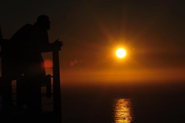 A tourist enjoys the view of sunset on the Signal Hill in Cape Town, South Africa, on Nov. 14, 2010. [Xinhua] 