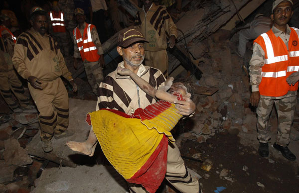 A rescue worker carries an injured girl at the site of a building collapse in New Delhi November 16, 2010. A residential building collapsed in Lalita Park in New Delhi&apos;s Laxmi Nagar area on Monday evening. [China Daily/Agencies]