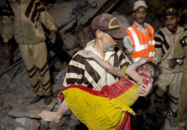 A rescuer carries an injured child at the site of building collapse in the Indian capital of New Delhi, on Nov. 15, 2010. As many as 65 people were killed and around 120 others injured when a 15-year-old four-story building collapsed in East Delhi Monday evening, said officials and police. [Xinhua]