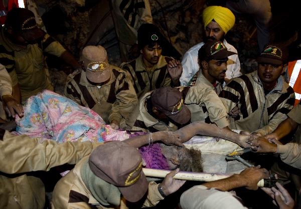 Rescuers carry an injured person at the site of building collapse in the Indian capital of New Delhi, on Nov. 15, 2010. As many as 65 people were killed and around 120 others injured when a 15-year-old four-story building collapsed in East Delhi Monday evening, said officials and police.[Xinhua]