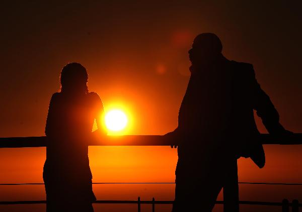 Two tourists enjoy the view of sunset on the Signal Hill in Cape Town, South Africa, on Nov. 14, 2010. [Xinhua/Liu Chan]