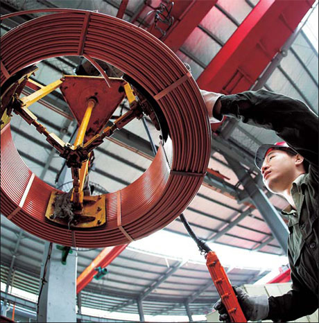 A worker operates machinery at a copper components factory in Zhejiang province. [China Daily]