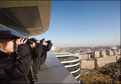 Staff members from Xicheng environment protection bureau use binoculars to check chimney emissions. [China Daily] 