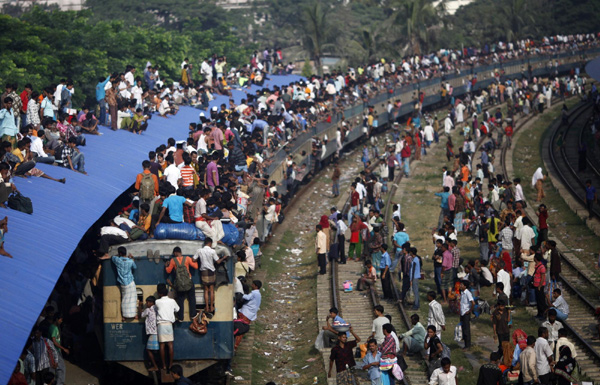 Passengers ride on top of an overcrowded train at a railway station in Dhaka, Nov 16, 2010. Millions of residents in Dhaka are travelling home from the capital city to celebrate the Eid al-Adha holiday on Wednesday. [China Daily/Agencies]