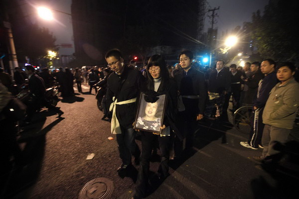 Residents mourn for their relatives at the entrance of the burnt apartment building in Shanghai, Nov 16, 2010. [China Daily/Agencies]