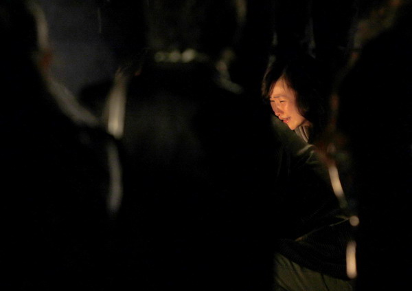 A woman mourns for her relatives at the entrance of the burnt apartment building in Shanghai, November 16, 2010. [China Daily/Agencies]