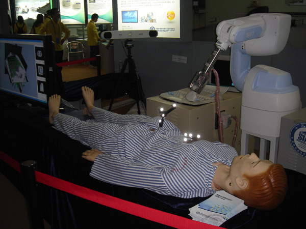 A surgical robot is seen performing a procedure on a manikin at the fair, Nov 16, 2010. The orthopedic surgery aid will offer a detection and guidance service during the implantation process of surgery. [chinadaily.com.cn]