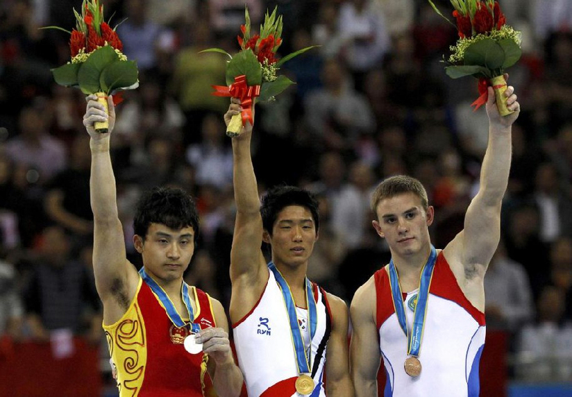 South Korea&apos;s Yang Hak-seon stands with his gold medal after the men&apos;s vault final during artistic gymnastics at the 16th Asian Games in Guangzhou, Guangdong province, November 17, 2010. China&apos;s Feng Zhe (L) received silver and Kazahstan&apos;s Stanislav Valiyev bronze. [China Daily/Agencies]