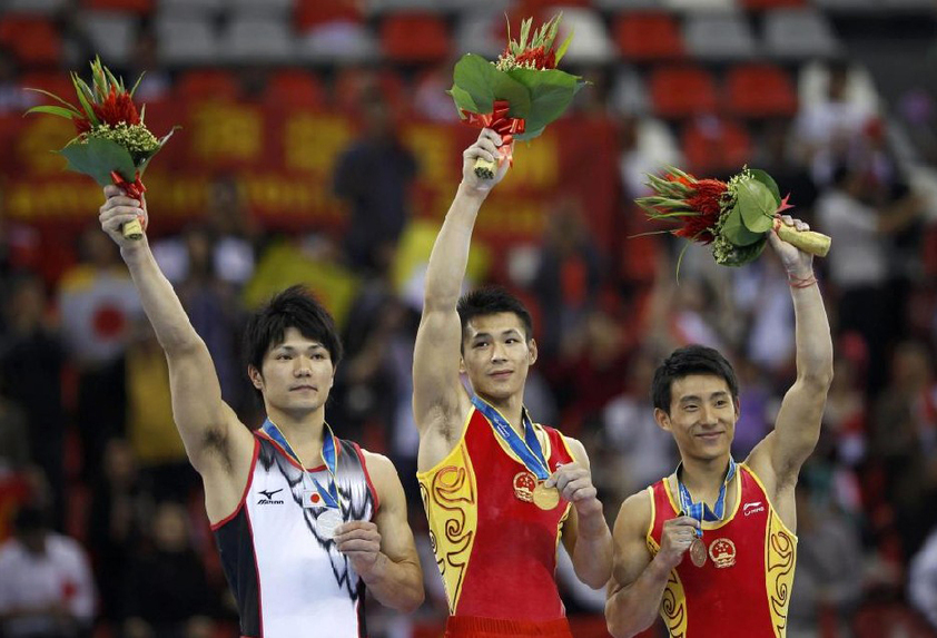 China&apos;s gold medalist Zhang Chenglong (C) stand&apos;s with Japan&apos;s silver medalist Shun Kuwahara and China&apos;s bronze medalist Teng Haibin after their men&apos;s horizontal bar final during artistic gymnastics at the 16th Asian Games in Guangzhou, Guangdong province, November 17, 2010. [China Daily/Agencies]