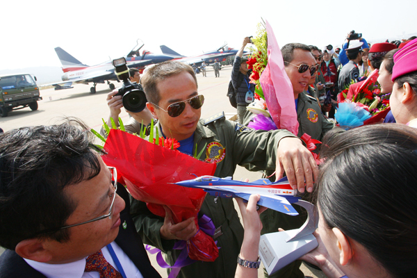 The 8th China International Aviation and Aerospace Exhibition kicks off in Zhuhai City, south China's Guangdong Province, on November 17, 2010. In the picture the top ten model Chinese air hostesses chosen by the Civil Aviation Administration of China present flowers to the stunt pilots of the August 1st Aerobatic Team of the Chinese PLA air force. [Xinhua photo]