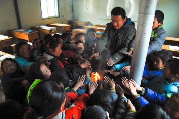 A second-grade student sits in a prefabricated classroom with a burning stove on Nov 15, 2010 in Yushu county, Qinghai province, which was hit by a 7.1-magnitude earthquake on April 14.