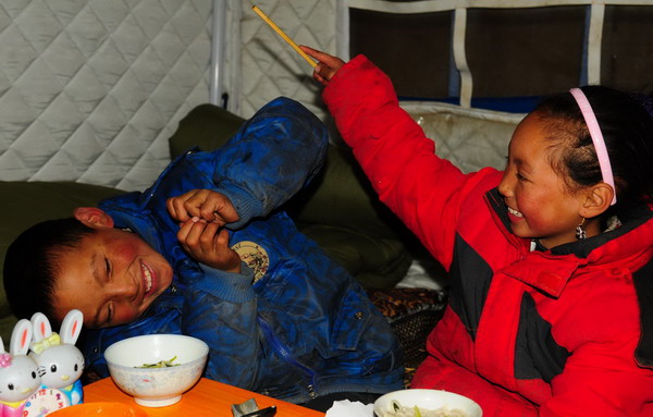 A Tibetan girl plays with her brother in their tent in Yushu, Qinghai province, Nov 17, 2010. [Xinhua]
