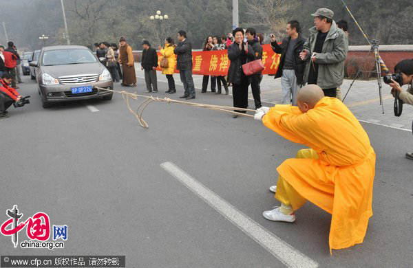 Hui Long, a female monk, pulls six cars forward at a parking lot at Tanzhesi Temple in Beijing, Nov 18,2010. [Photo/CFP]
