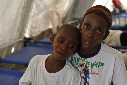 A Haitian boy with cholera symptoms grimaces next to his mother at a improvised clinic run by Doctor without Borders in Port-au-Prince, the capital of Haiti, Nov 20, 2010. [China Daily/Agencies] 