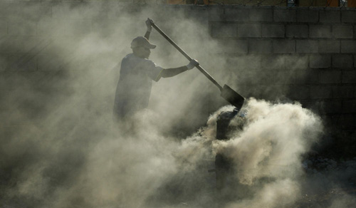 A worker from the Red Cross burns medical supplies used to control cholera next to a clinic in Port-au-Prince, the capital of Haiti, Nov 20, 2010. [China Daily/Agencies]