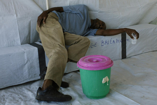 A man suffering from cholera symptoms wait for assistance at a makeshift clinic in Port-au-Prince, the capital of Haiti, Nov 20, 2010. [China Daily/Agencies] 