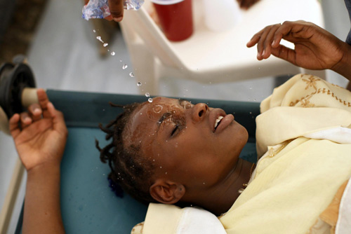 A Haitian girl with cholera symptoms is doused with water at an improvised clinic run by Doctors Without Borders in Port-au-Prince, the capital of Haiti, Nov 20, 2010. [China Daily/Agencies]