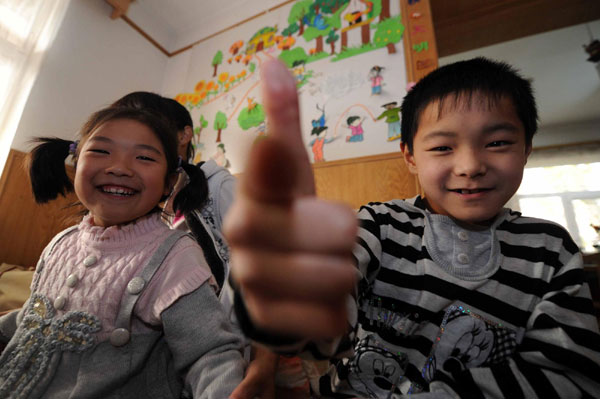 Zhang Weishi (R), 9, and Liu Chongyun (L), 8, play in the living room of the Children&apos;s Village in Tianjin on Nov 20, 2010. [Xinhua]