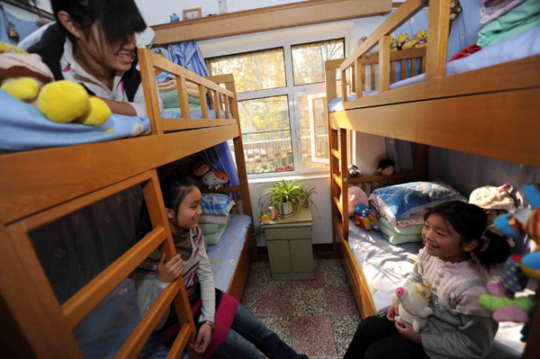 Zhang Weishi (R), 9, and Liu Chongyun (L), 8, play in the living room of the Children&apos;s Village in Tianjin on Nov 20, 2010. [Xinhua]