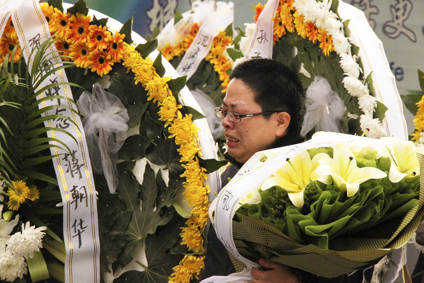 A citizen presents flowers to mourn victims of the deadly blaze in Shanghai, east China, Nov. 21, 2010. [Xinhua]