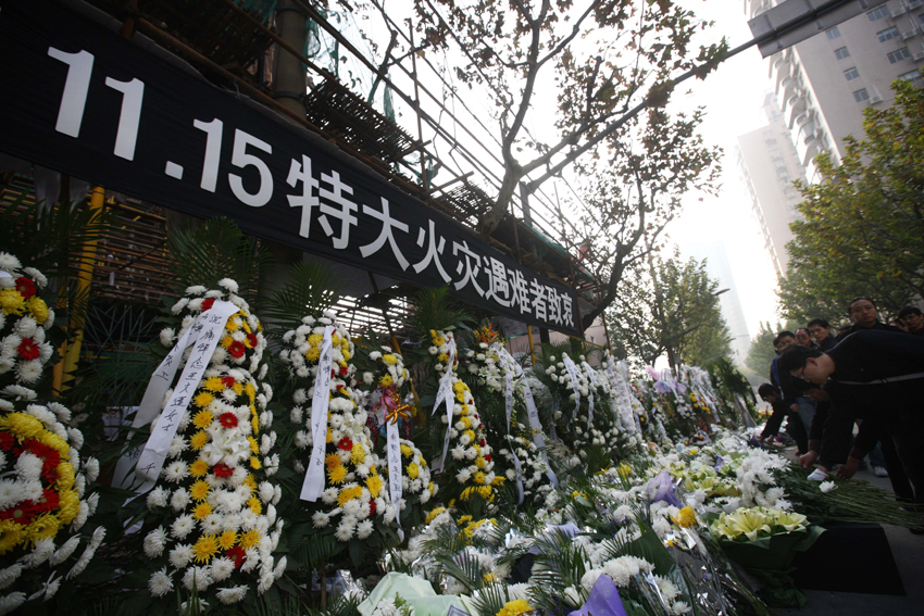 Citizens present flowers to mourn victims of the deadly blaze in Shanghai, east China, Nov. 21, 2010. [Xinhua]