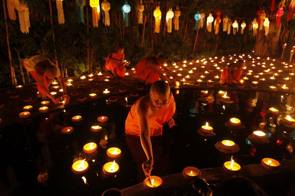 Buddhist monks light candles at a temple in Chiang Mai during the annual Loy Krathong festival November 21, 2010. [China Daily/Agencies]