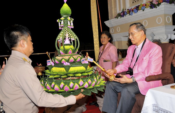 Thailand&apos;s King Bhumibol Adulyadej lights the candle of a krathong before floating the krathong onto a river during the Loy Krathong festival at Siriraj Hospital in Bangkok November 21, 2010. [China Daily/Agencies]