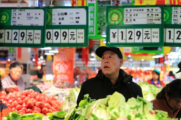 A customer calculates vegetable prices at a supermarket in Beijing. [China Daily]