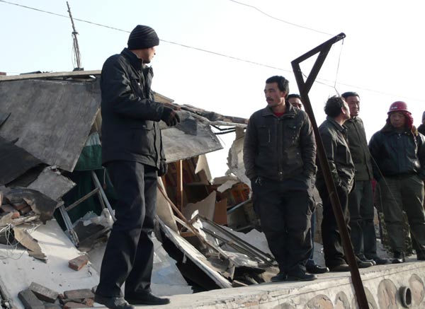 Villagers stare at what is left of the plant on Sunday. Behind them are shacks that collapsed due to the explosion.