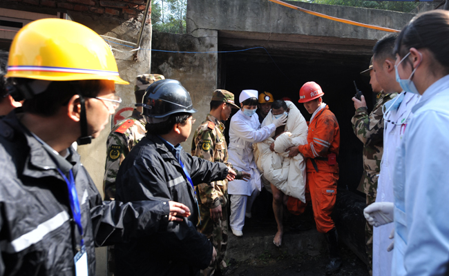 A miner, his eyes protected against the glaring light, is escorted out of the flooded mine in Weiyuan, Sichuan province, on Monday. Emergency services resuced all 29 men after they were trapped when water inundated the Batian Coal Mine at 11:40 am on Sunday. [Xinhua] 