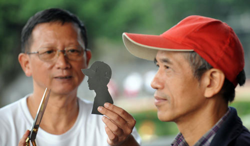 A street artist makes a paper-cut silhouette of a passer-by in Taipei, Taiwan, Nov 21, 2010. A total of 281 art-savvy individuals and teams gathered at Yixian Park to apply for street art permits issued by the local bureau of culture. The event has handed out licenses to nearly 900 street performers in Taiwan since it started in 2005. [Xinhua] 