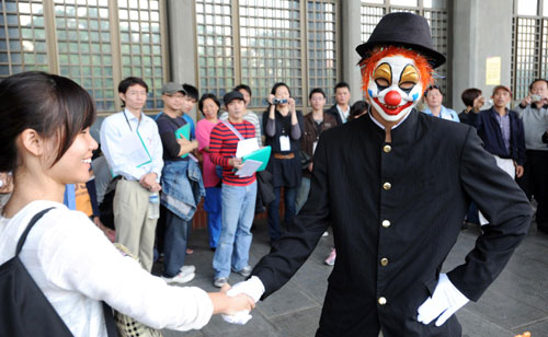 A clown shakes hands with a passer-by while performing at Yixian Park in Taipei, Taiwan, Nov 21, 2010. [Xinhua] 